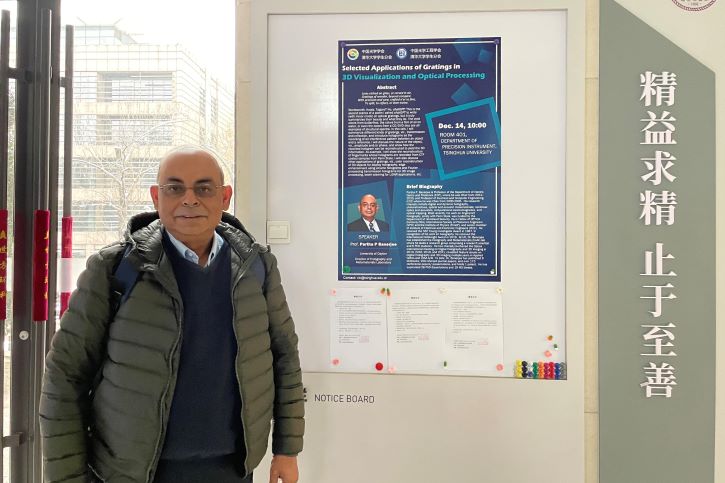 Dr. Banerjee standing in front of the poster advertising his lecture