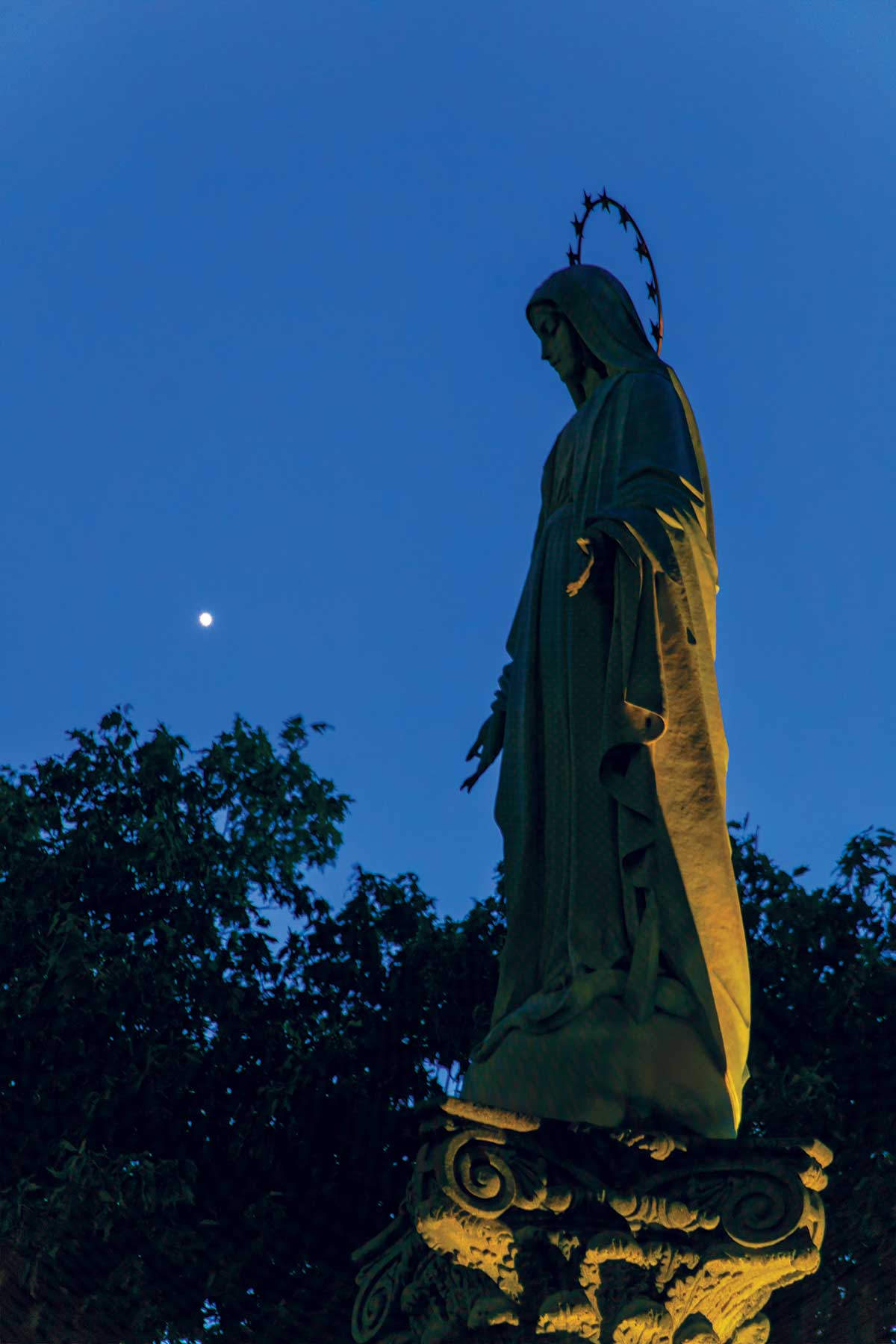 A star hangs in the sky right behind the statue of Mary on campus.
