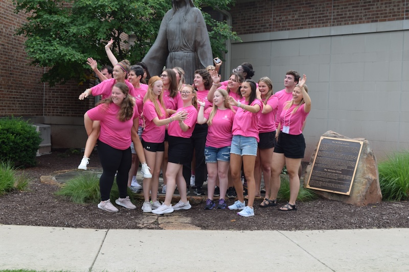 ${ group of students smiling and laughing, wearing bright pink shirts  }