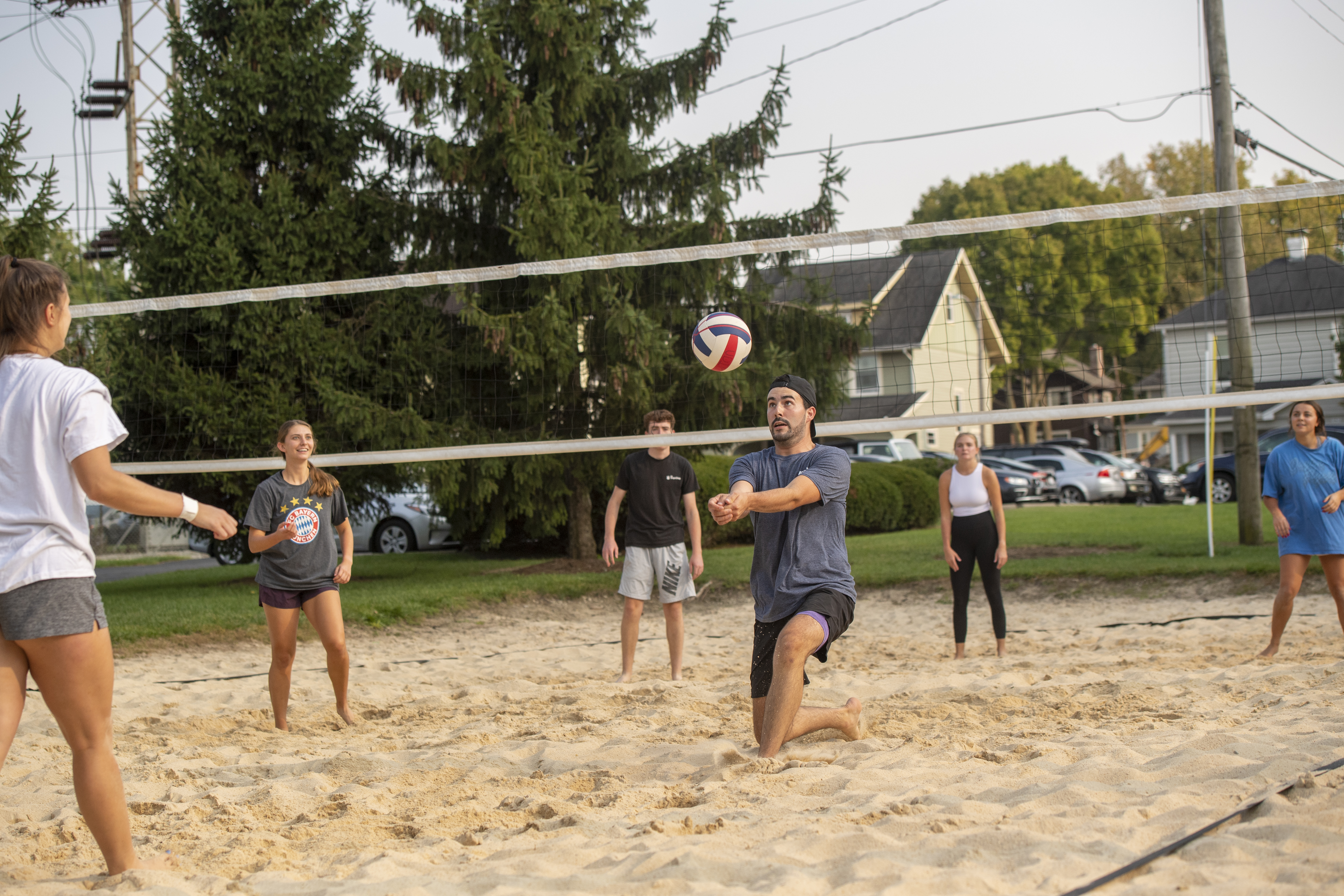 ${ Participant playing sand volleyball preparing to bump the ball up to their teammates. }